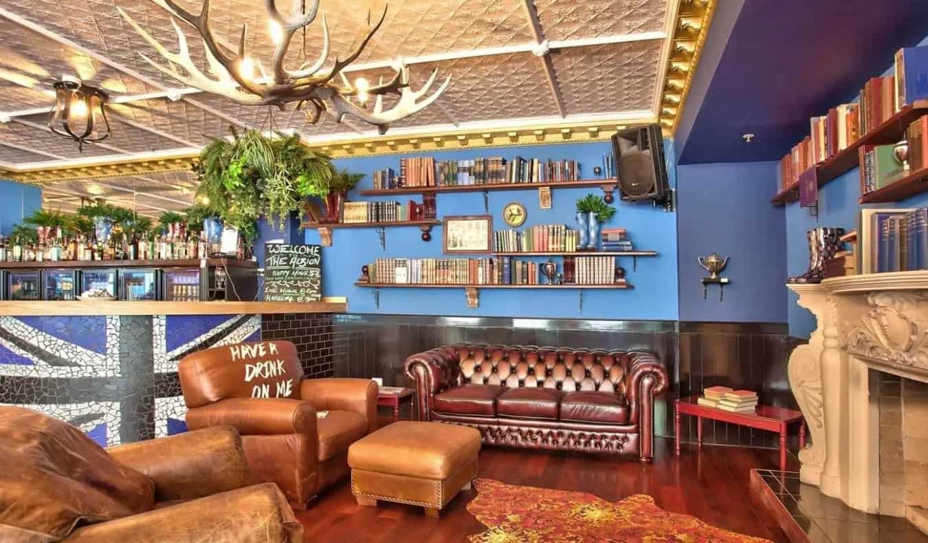 Cozy common area at the Albion hotel with leather couches, a fireplace, and a chandelier made of antlers, at The Albion hotel in Auckland, New Zealand