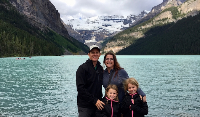 Amanda and her traveling family posing near a lake with mountains in the background