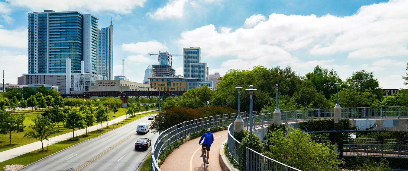 A man cycling on a narrow walkway in Austin, Texas