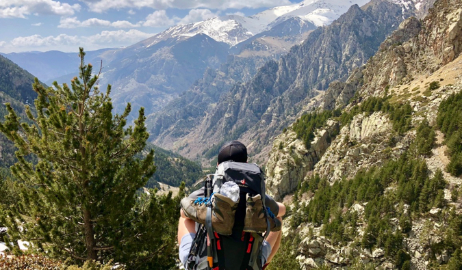 A budget backpacker sitting on a mountain looking into the distance