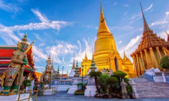 golden spires of temples in Bangkok set against a bright blue sky