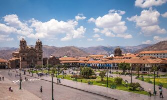 The sprawling Plaza de Armas with rolling mountains in the background in the historic center of Cusco, Peru