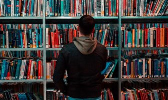 A man looking at a bookshelf in a library