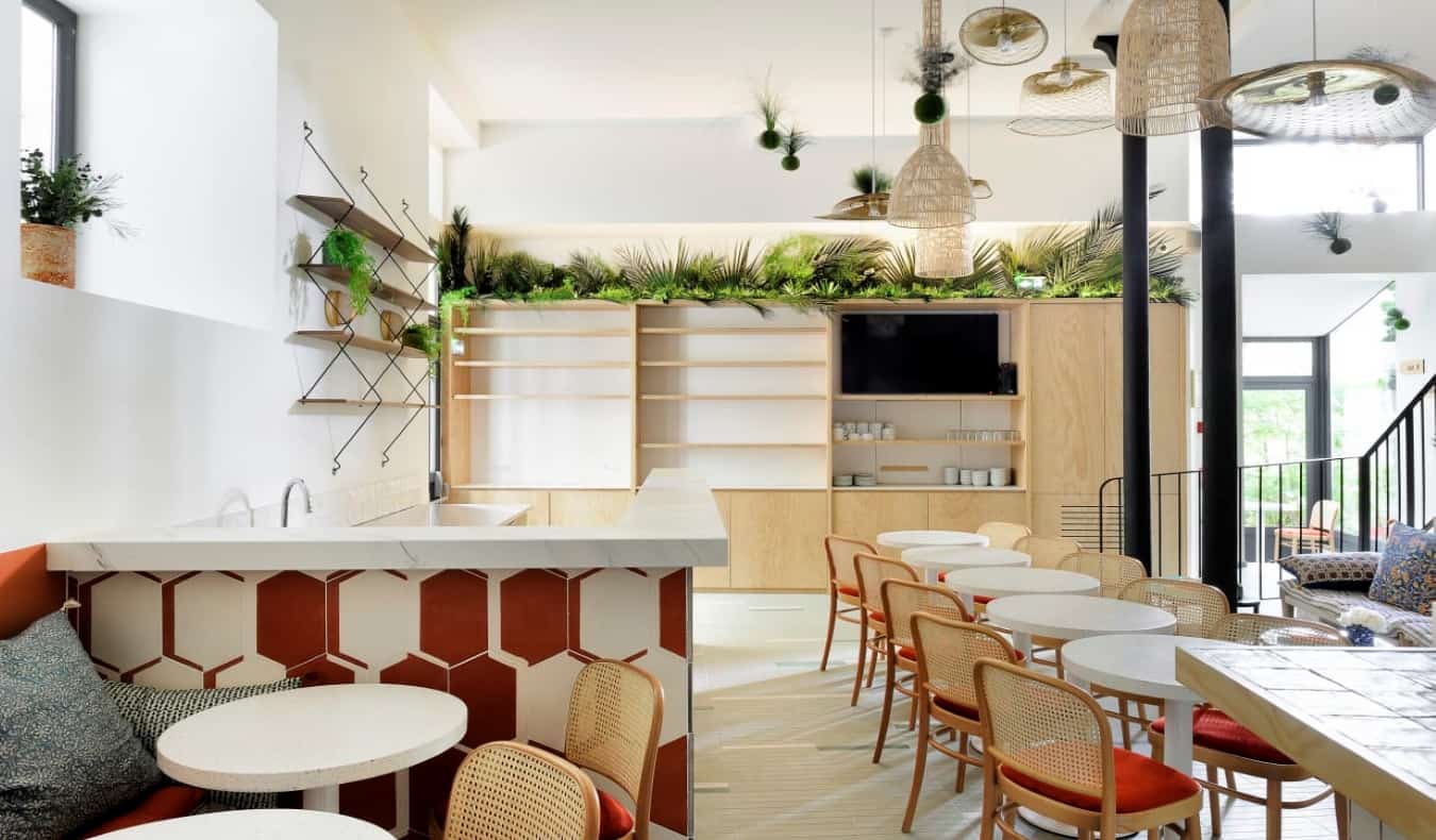 Bright, light-filled common area with lots of round tables and chairs at Caulaincourt hostel in Paris