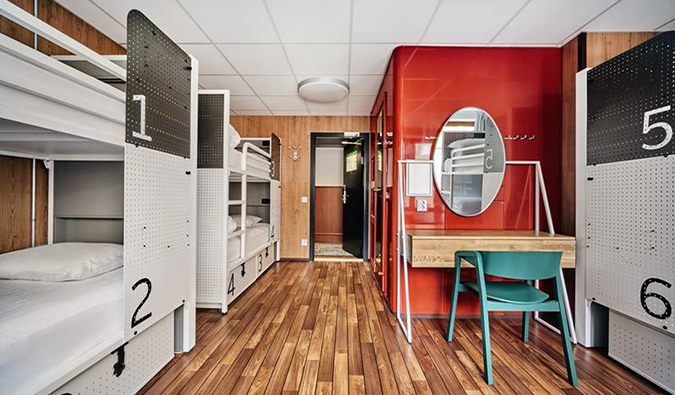 White metal bunk beds labeled with numbers in dorm room with wooden floors at Generator Hostel, Stockholm