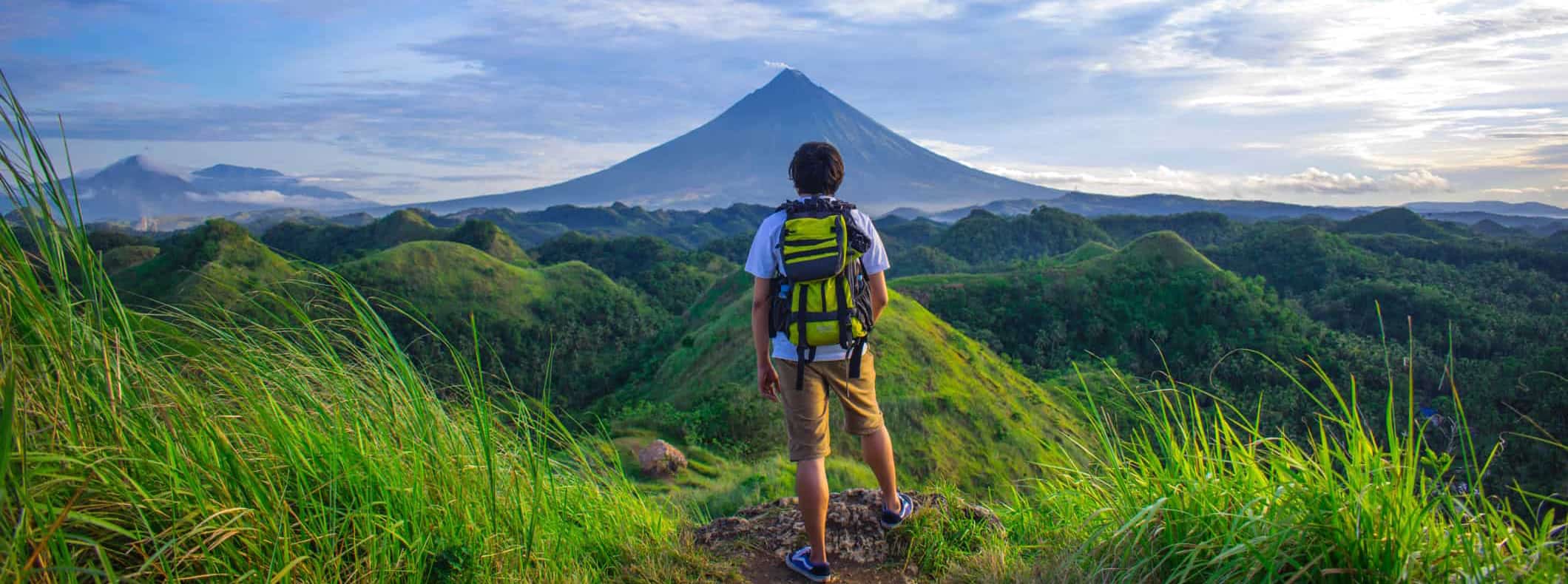 A lone solo traveler posing near a mountain while traveling abroad