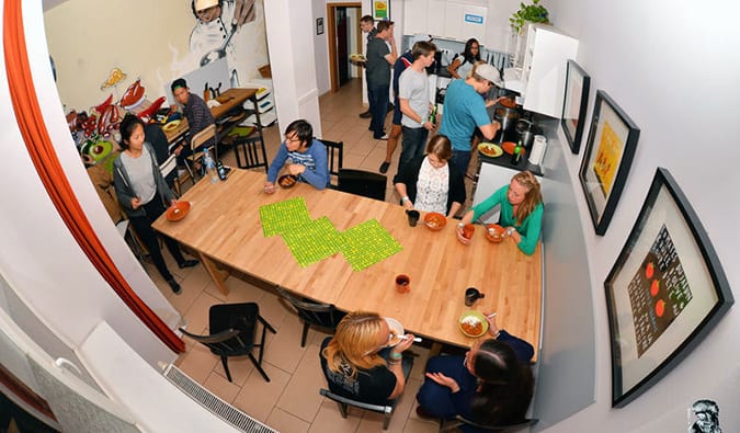 Fisheye style photo of kitchen at Onefam in Prague, with people sitting at a table, preparing food, eating, and talking.