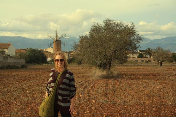 Jessica, a female traveler and backpacker posing for a photo in a field in Europe