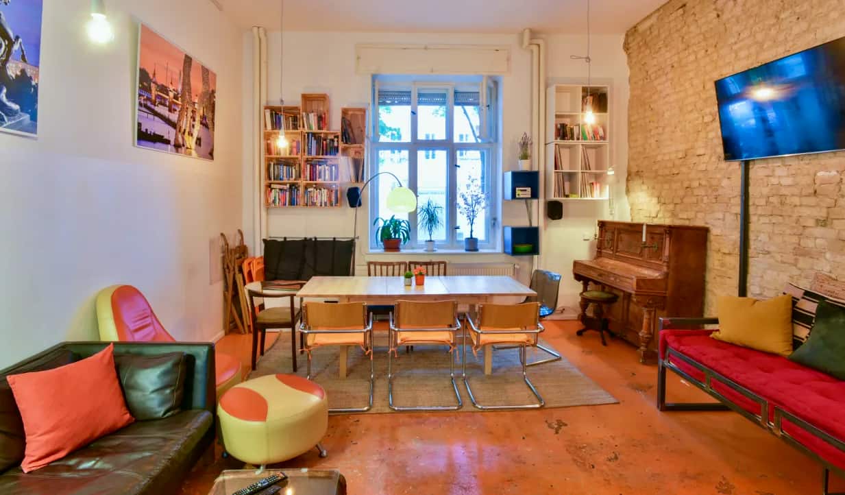 Kitchen area with long wooden table and hanging lamps made of wine bottles at Minimal Hostel Berlin, Berlin