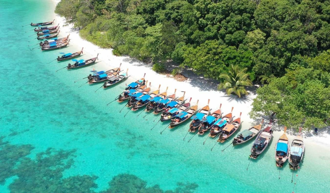 Aerial view of a line of longtail boats docked on a beach on the island of Ko Lipe, Thailand