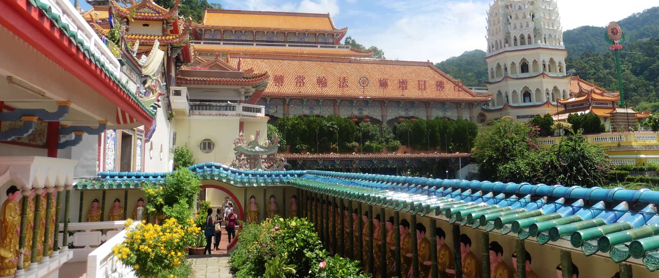 Colorful historic temples in Malaysia on a sunny day with rolling green hills in the background