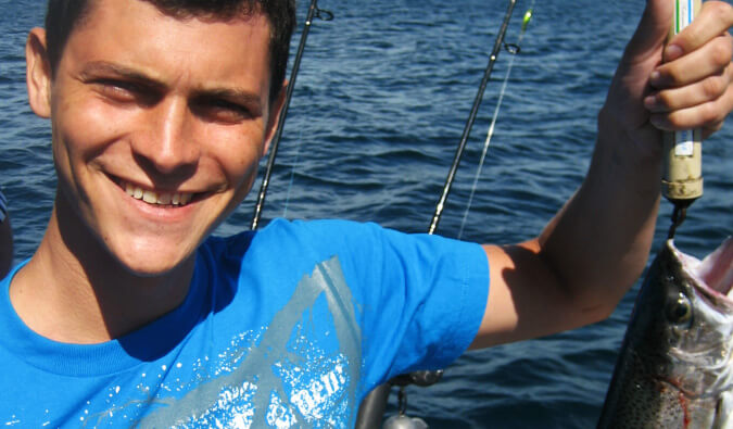 Nomadic Matt on a boat fishing holding up a fish he caught