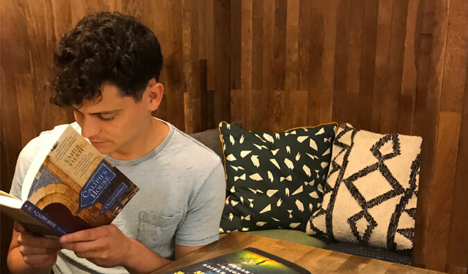 Nomadic Matt reading a book seated in a corner booth