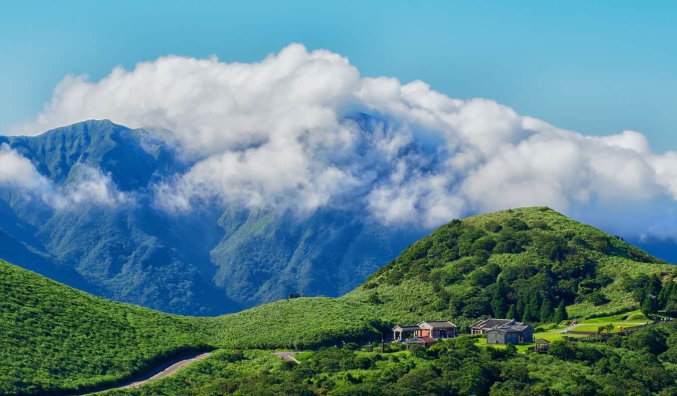 Green mountains covered in clouds with a small village in the foreground in Taiwan