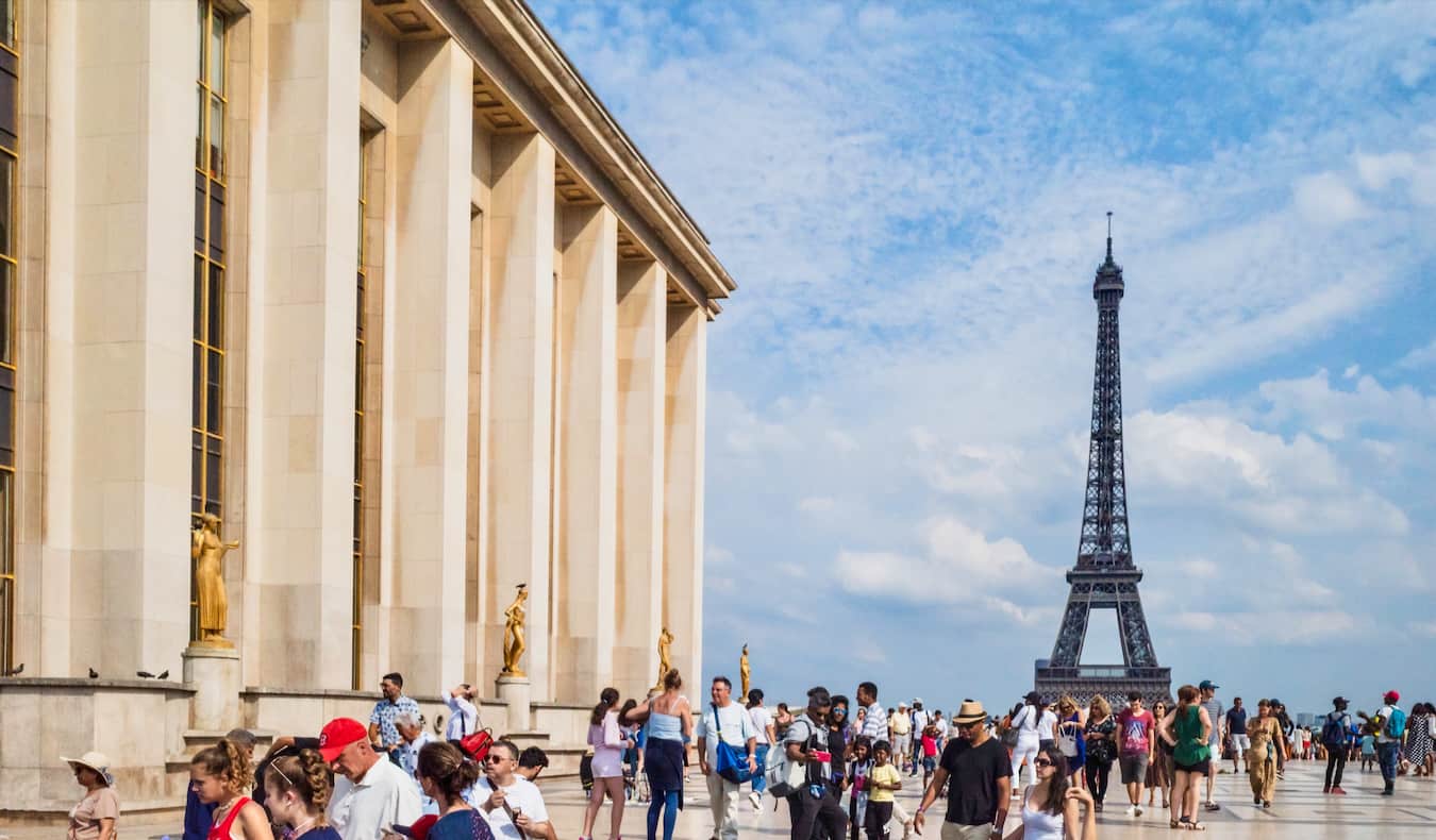 A crowd of travelers near the Eiffel Tower in sunny Paris