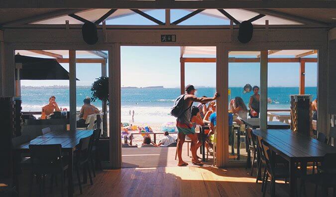 empty restaurant looking out to the beach with people eating on the terrace sea in background