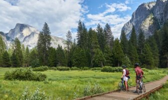 Two people on bikes stop and admire the landscape of forests and mountains at Yosemite Park in the United States