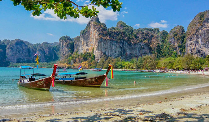 colorful long boats tied up on a Thai beach