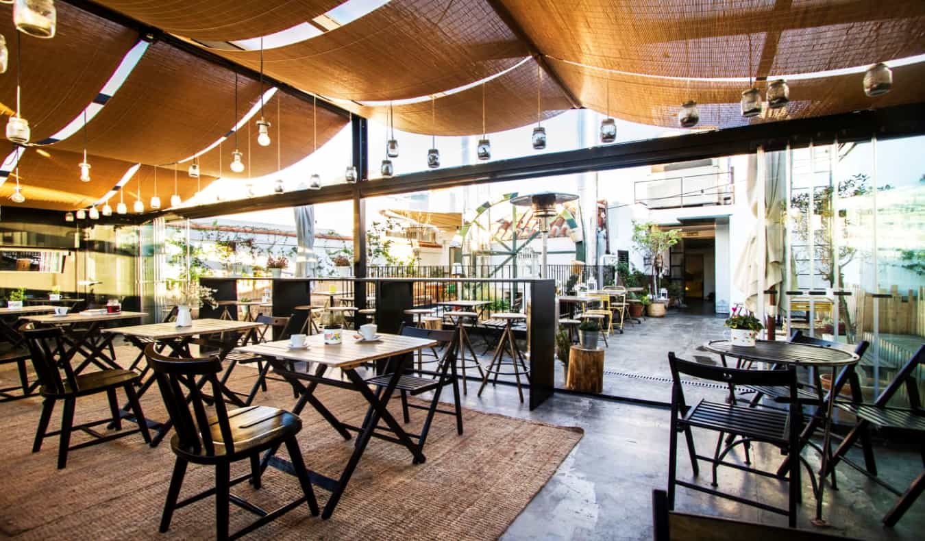 Rooftop terrace with covered and uncovered portions, with chairs and table for seating at The Hat Hostel in Madrid, Spain.