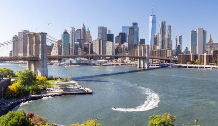 Panoramic view of the Manhattan skyline across the East River with the Brooklyn Bridge in the foreground