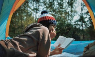 A traveler reading a book while inside a tent