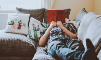 A man reading a book while sitting on his couch