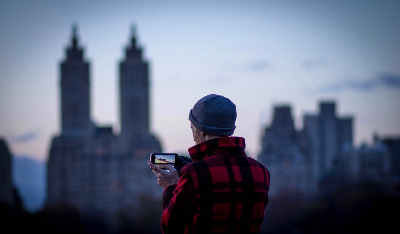 A man using a smartphone to take pictures of a city