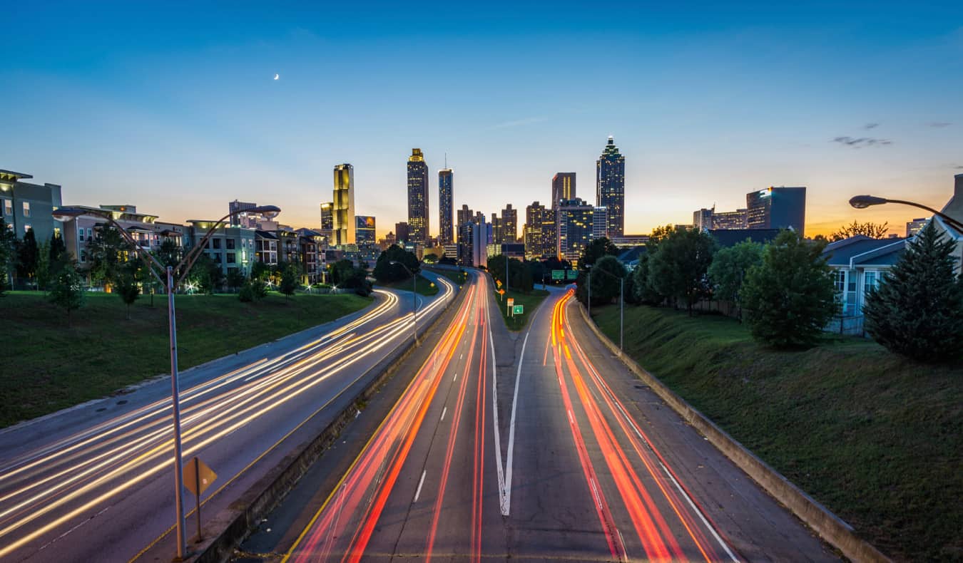 The skyline of Atlanta, GA lit up at night over the highway