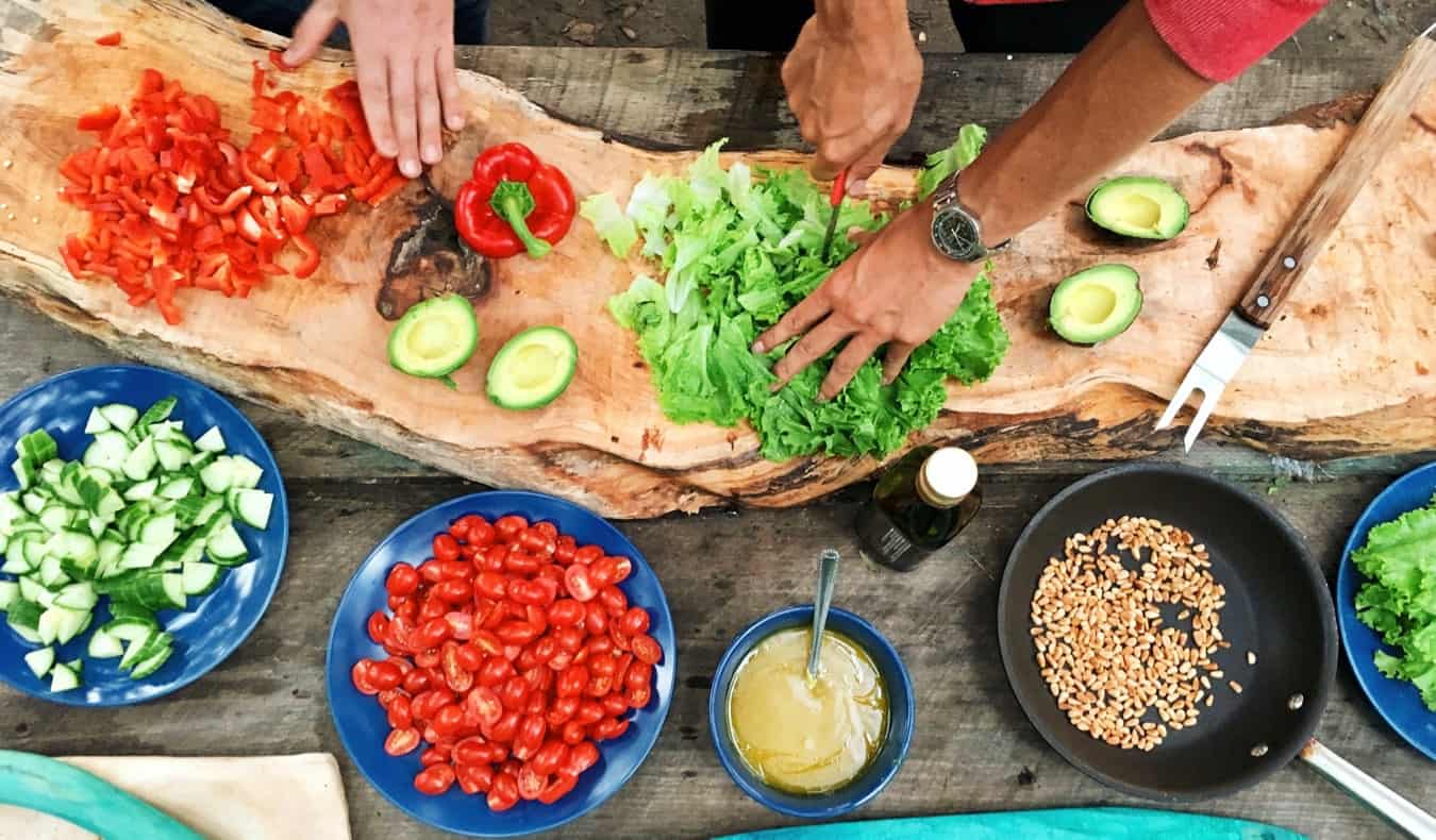 Two people cooking an exotic, colorful dish on a kitchen counter